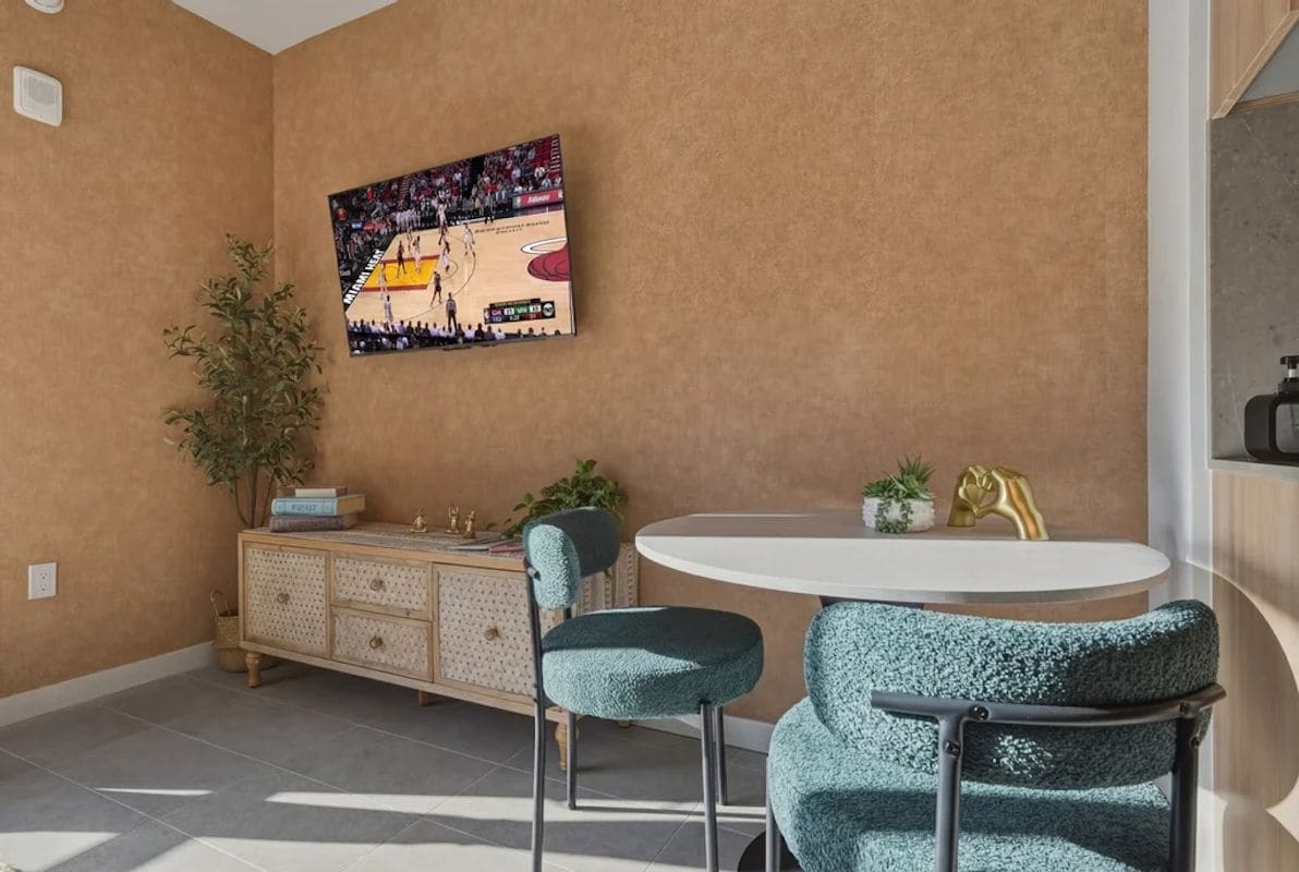 Un comedor con una mesa redonda, dos sillas, un aparador con objetos decorativos y un cuadro colgado en la pared.