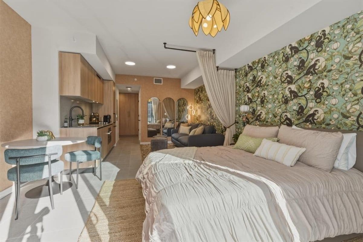 Un dormitorio moderno con una cama grande, una zona de comedor con mesa y sillas, una cocina y una sala de estar con sofá.