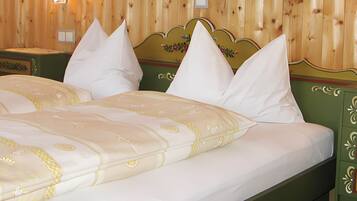Ein Bett mit blumigem Bettbezug und mehreren Kissen, ein Holz-Kopfbrett und ein grüner Nachttisch mit Schubladen.