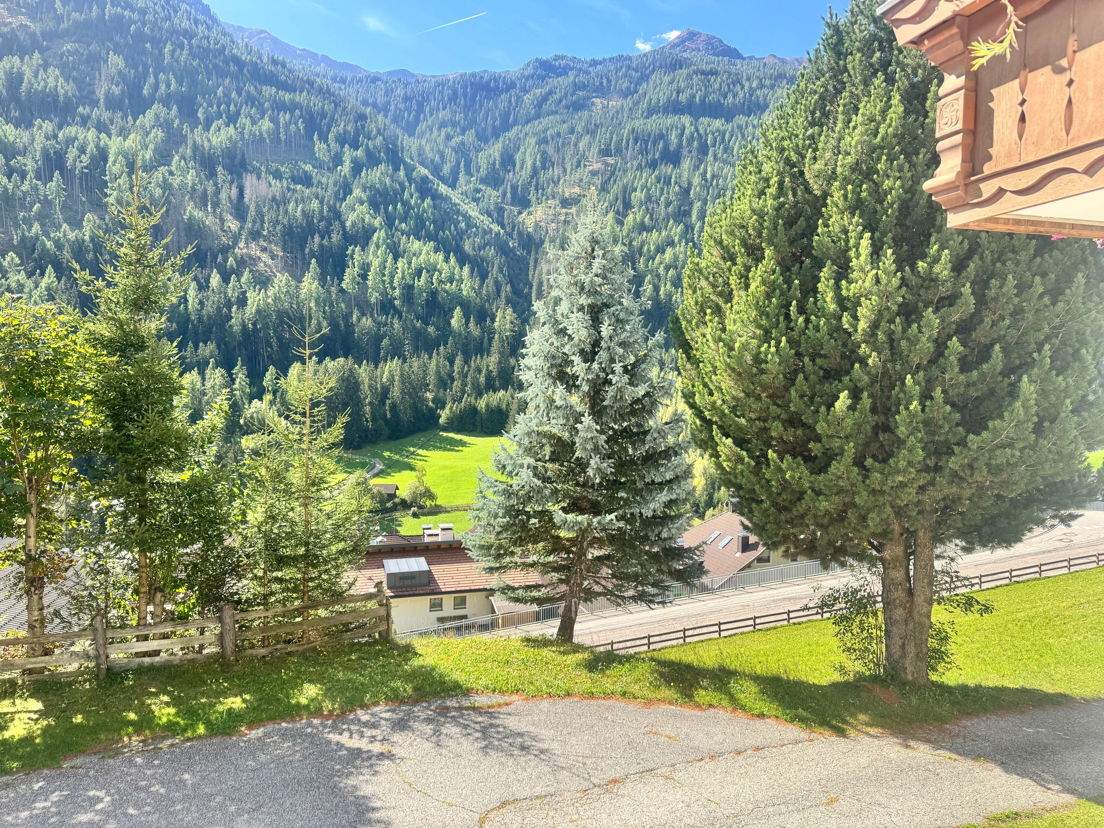 A mountainous landscape with a clear sky, a fenced property, and a building with a sloped roof.