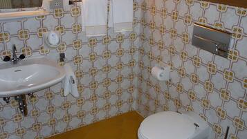 Ein Badezimmer mit weißem Waschbecken, Toilette und Handtuchhalter.