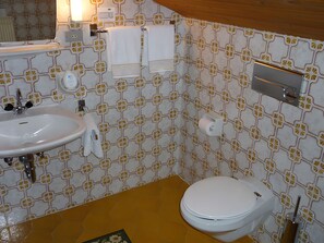 Une salle de bain avec un lavabo blanc, des toilettes et un porte-serviettes.