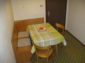 A small dining area with a table covered by a patterned tablecloth, a bowl of fruit, and a wooden bench. - Apartment '1' with Mountain View, Shared Garden and Wi-Fi (Selva dei Molini)