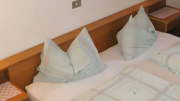 Une chambre d’hôtel avec une tête de lit en bois, deux oreillers, une table de chevet avec une lampe et un lit recouvert d’une couvre-lit à motifs.