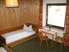 A room with a wooden bunk bed, a small table with chairs, a radiator, and a window with curtains. - Apartment '1' with Mountain View, Shared Garden and Wi-Fi (Selva dei Molini)