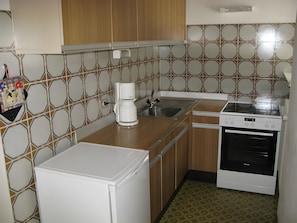Cocina compacta con cafetera, lavamanos y estufa.