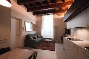 Un espace de vie compact comprenant un canapé, une table à manger et un coin cuisine.