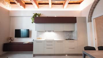 A modern kitchen with white cabinets, a marble backsplash, and a wooden ceiling.