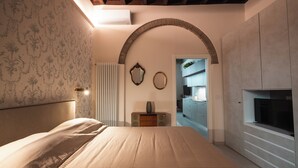 Quarto com uma cama, radiador, espelho e televisão.