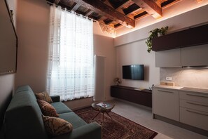 Una sala de estar moderna con un sofá, un televisor de pantalla plana y una zona de cocina.