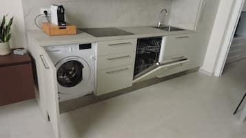 A compact kitchen with a built-in washing machine, a sink, and a dishwasher.