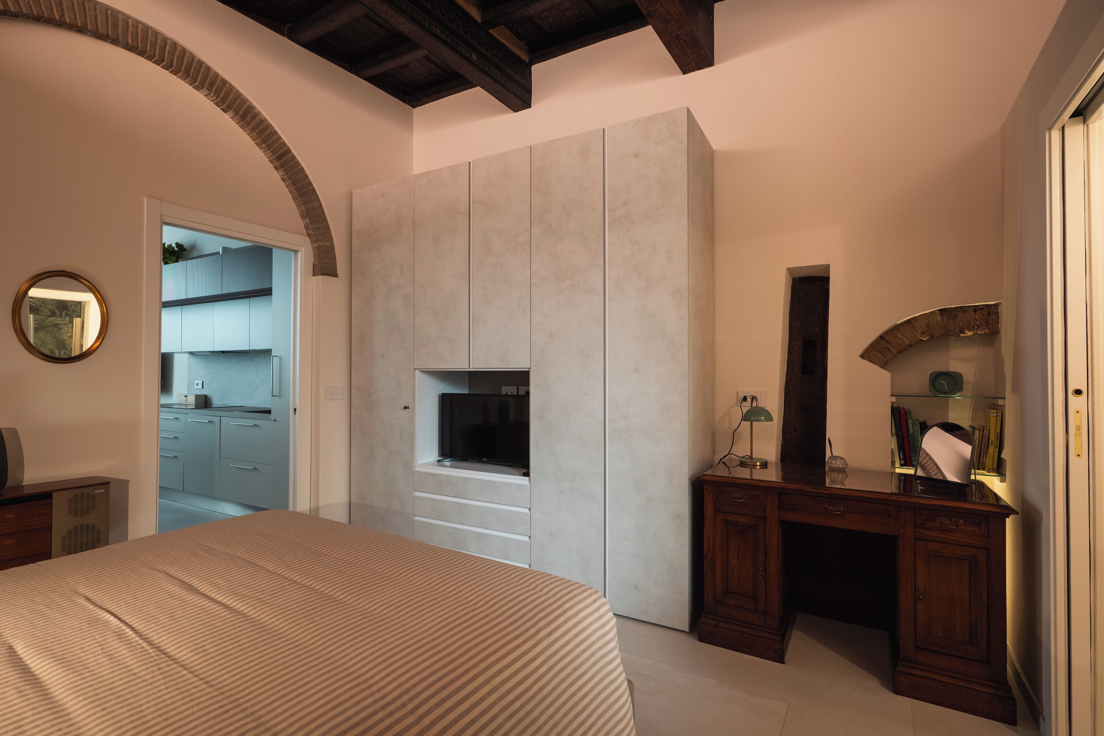 Ein Schlafzimmer mit Bett, Schrank, Schreibtisch und Fernseher.