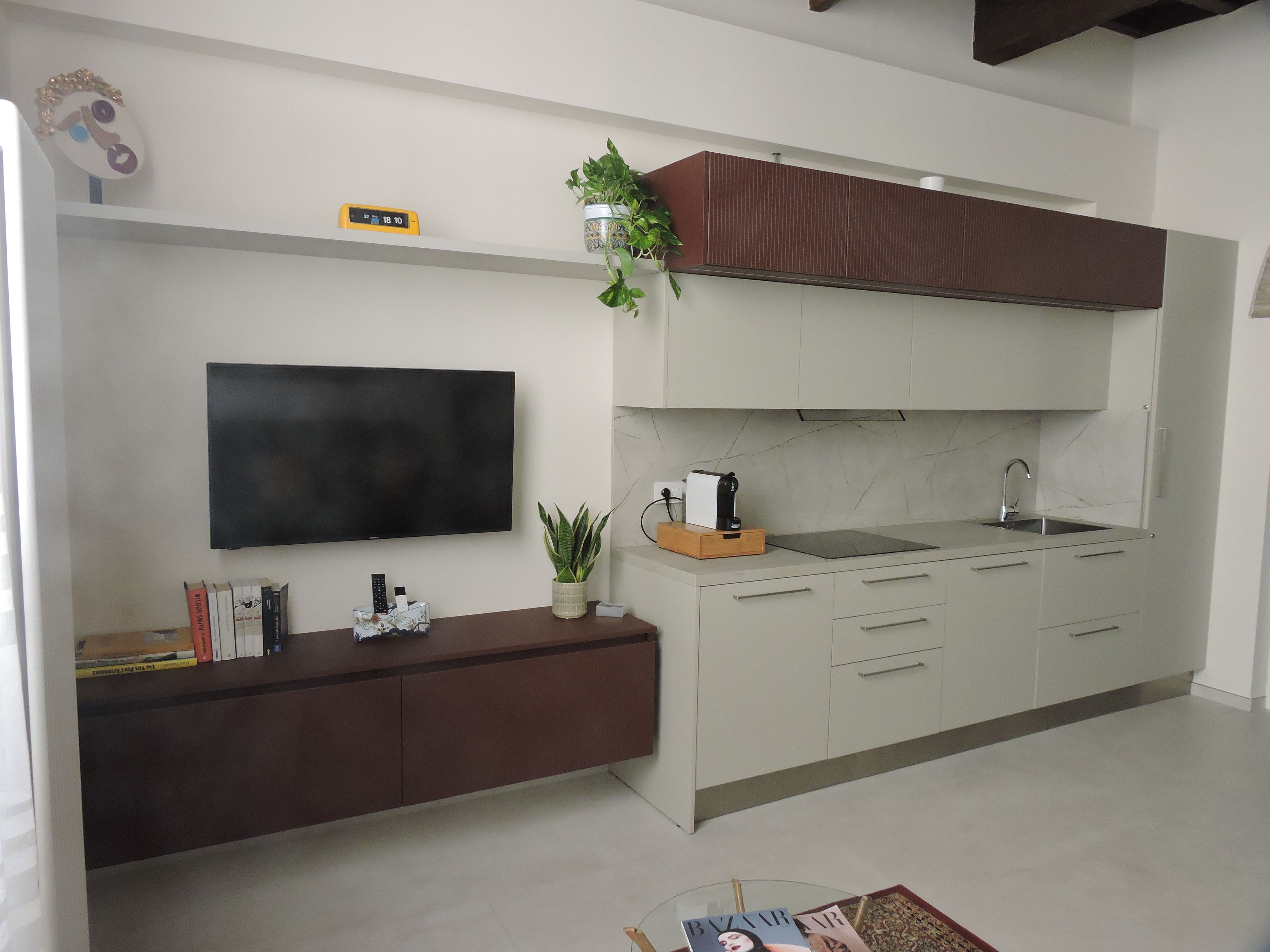 A modern kitchen with a flat-screen TV, a coffee machine, and a sink.