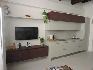 Una cocina moderna con televisor de pantalla plana, cafetera y lavaplatos.