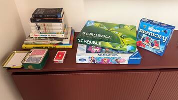 Ein Schreibtisch mit verschiedenen Gesellschaftsspielen und Puzzles, darunter Scrabble, Memory und ein großes Bodenpuzzle.