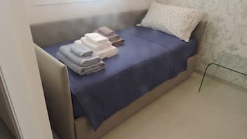 A compact bed with a blue bedspread and a white pillow with a dotted pattern.