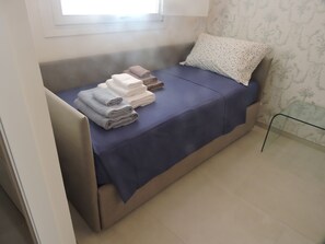 A compact bed with a blue bedspread and a white pillow with a dotted pattern.