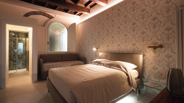 Quarto com cama, mesa de vidro e área de chuveiro.