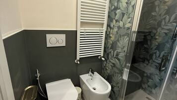 Ein Badezimmer mit Toilette, Bidet und Duschbereich.