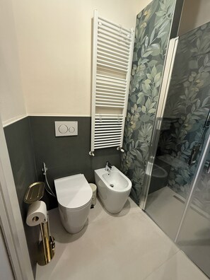 Une salle de bain comprenant des toilettes, un bidet et un espace douche.