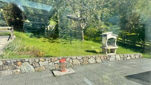 A stone wall with a stone bench and a small stone structure, possibly a birdhouse, in a grassy area with trees in the background. - Apartment '2' with Mountain View, Private Terrace and Wi-Fi (Selva dei Molini)