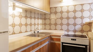 Eine Küche mit Holzausstattung, einem Edelstahlspülbecken, einem Einbauofen und einer Fliesenrückwand mit Muster.