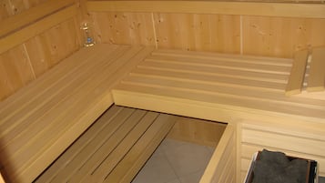 Eine Sauna mit Holzwänden und -bänken, einem gefliesten Boden und einer kleinen Spüle.