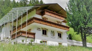 Un immeuble à plusieurs étages doté de balcons, entouré de verdure.