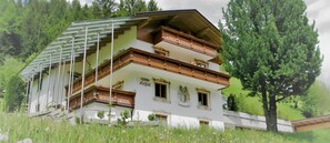 Un immeuble à plusieurs étages doté de balcons, entouré de verdure.