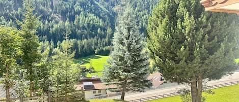 A mountainous landscape with a clear sky, a fenced property, and a building with a sloped roof.