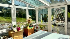 A conservatory with a glass ceiling, a wooden table, and various potted plants. - Apartment '2' with Mountain View, Private Terrace and Wi-Fi (Selva dei Molini)