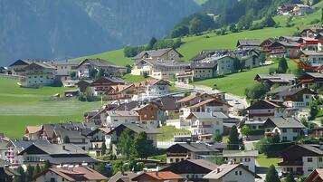 Ein Dorf an einem Hang mit traditionellen Häusern, einer Kirche und einem Berg im Hintergrund.