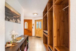 A hallway with a wooden bench, a wall-mounted shelf with items, a door with glass panels, and a framed picture on the wall. - Apartment 'Rackhof' with Mountain View, Private Terrace and Wi-Fi (Oberlienz)