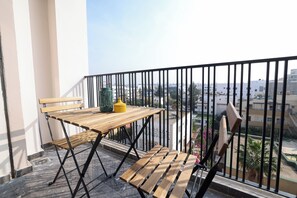 A balcony with a wooden table and chairs, a green lantern, and a view of the cityscape. - Stylish 1BR apartment in central Casablanca with Terrace & Parking (Dar-el-Beida)