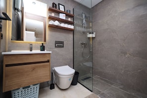 A modern bathroom with a glass shower enclosure, a wooden vanity, and a toilet. - Stylish 1BR apartment in central Casablanca with Terrace & Parking (Dar-el-Beida)