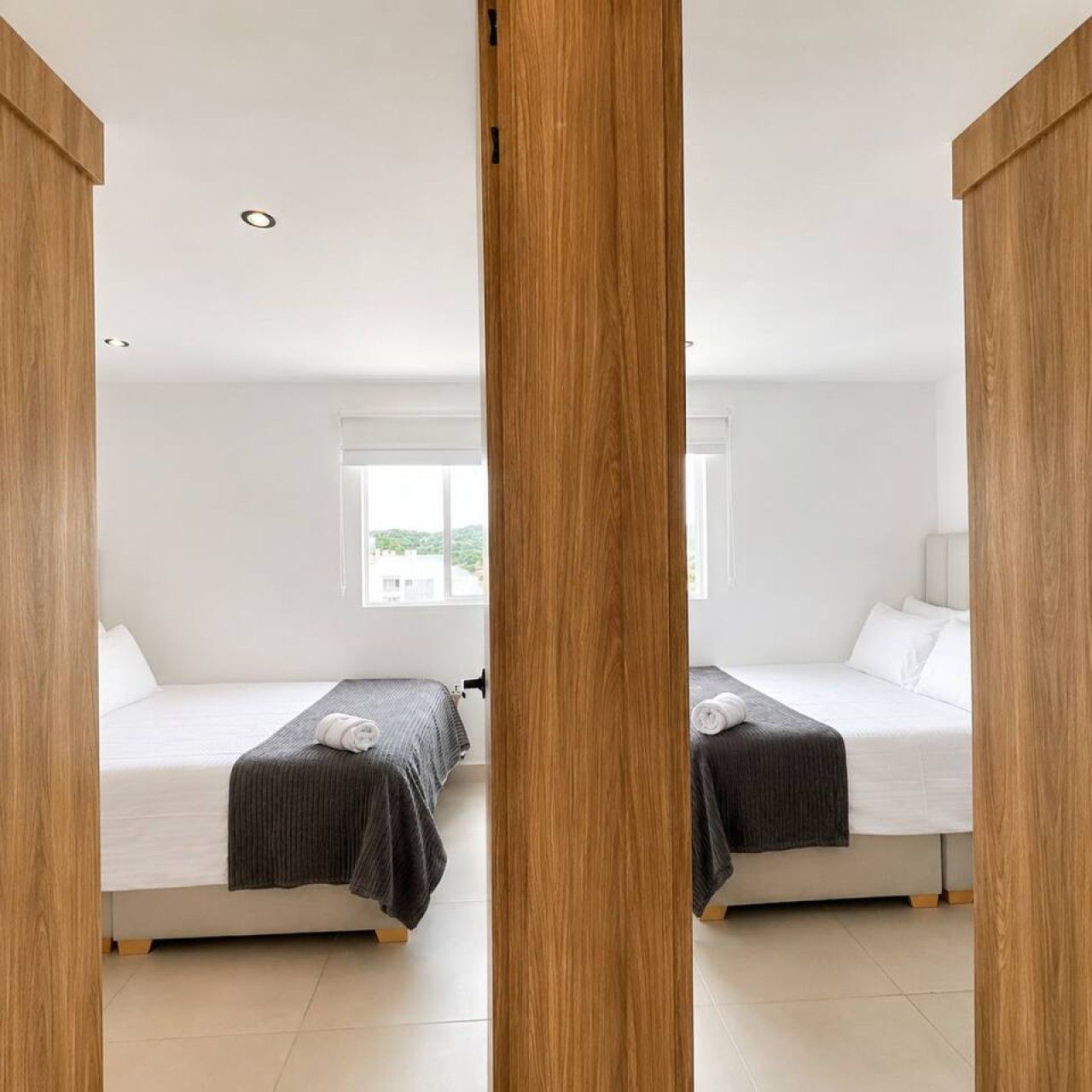 A hotel room with two beds, a window, and a wooden partition.