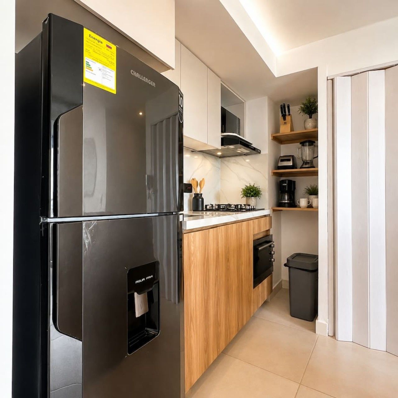 Una cocina moderna con refrigerador negro, armarios de madera y lavavajillas integrado.