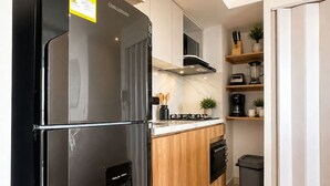 Een moderne keuken met een zwarte koelkast, houten kastjes en een inbouwvaatwasser.