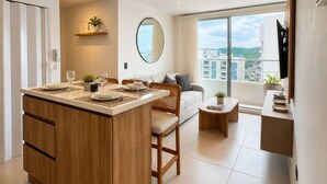 Een modern appartement met een kookeiland, een eethoek, een woongedeelte met een bank en een balkon met uitzicht op de stad.