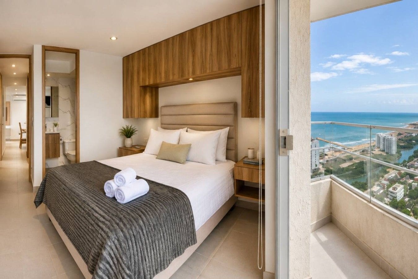 A modern hotel room with a large bed, a view of the city, and a balcony.