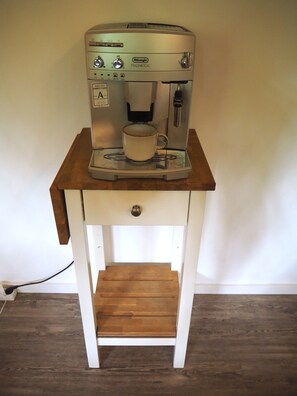 A coffee machine on a wooden table with a drawer below. - Cozy garden studio centrally located near the Kronberg train station (Kronberg im Taunus)