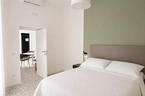 A bedroom with a bed, a bedside table, a lamp, and a door leading to a dining area. - Don Filippo Luxury Home - Vesuvia (Naples)