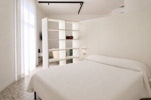 Ein Schlafzimmer mit einem Bett, einem weißen Kleiderschrank und einer Tür zu einem Badezimmer.