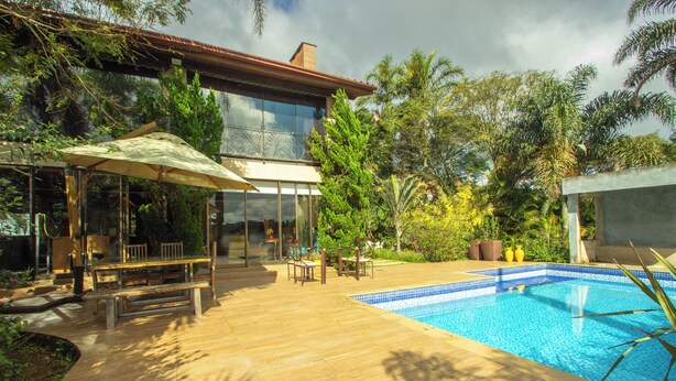Ein modernes Haus mit Wintergarten, Holzterrasse und Swimmingpool.