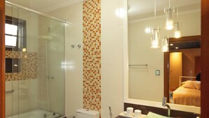 Ein modernes Badezimmer mit Duschkabine aus Glas, Toilette, Waschtisch mit Spiegel und Waschbecken.