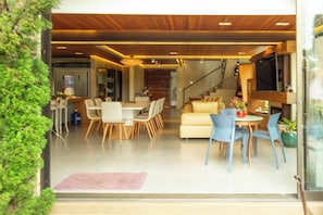 A modern interior with a dining area, sofas, and a staircase.