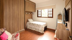 Ein Schlafzimmer mit Bett, Schrank, Fenster und Fernseher.