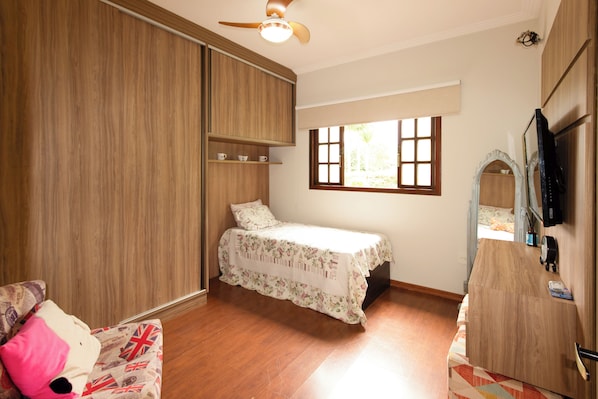 A bedroom with a bed, a wardrobe, a window, and a television. - House by the dam in Juiz de Fora | pool and nature (Juiz de Fora)
