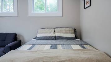 Une chambre à coucher avec un lit, une chaise et deux fenêtres.