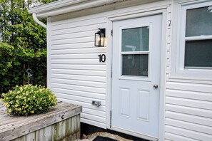 A white house with a number '10' on the door, a small porch with a planter, and a window with a screen.